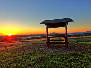 Lifeguard hut on field against sky during sunset