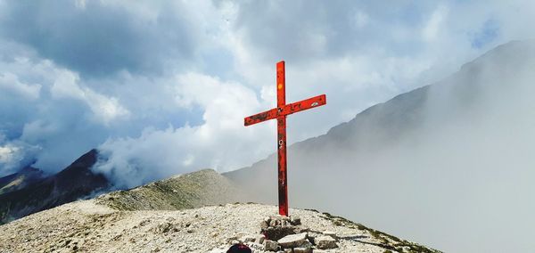 Cross on mountain against sky