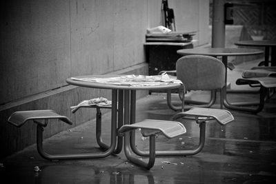 Empty chairs and table against wall