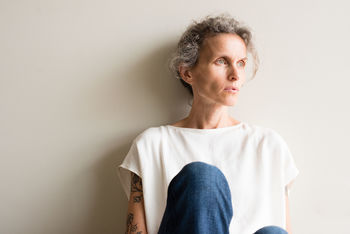 Close-up of a woman sitting by wall