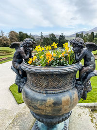 Close-up of yellow statue by plants against sky