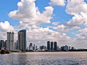 Sea by modern buildings against sky in city