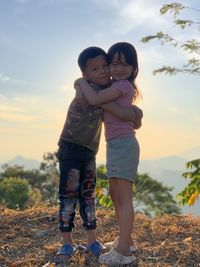 Portrait of boy standing on rock against sky during sunset