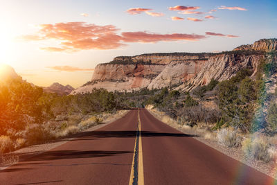 Road amidst rocks against sky during sunset