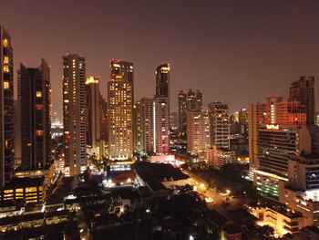 Illuminated buildings in city against sky at night