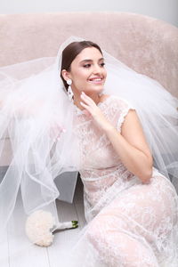 Portrait of smiling young woman sitting on bed