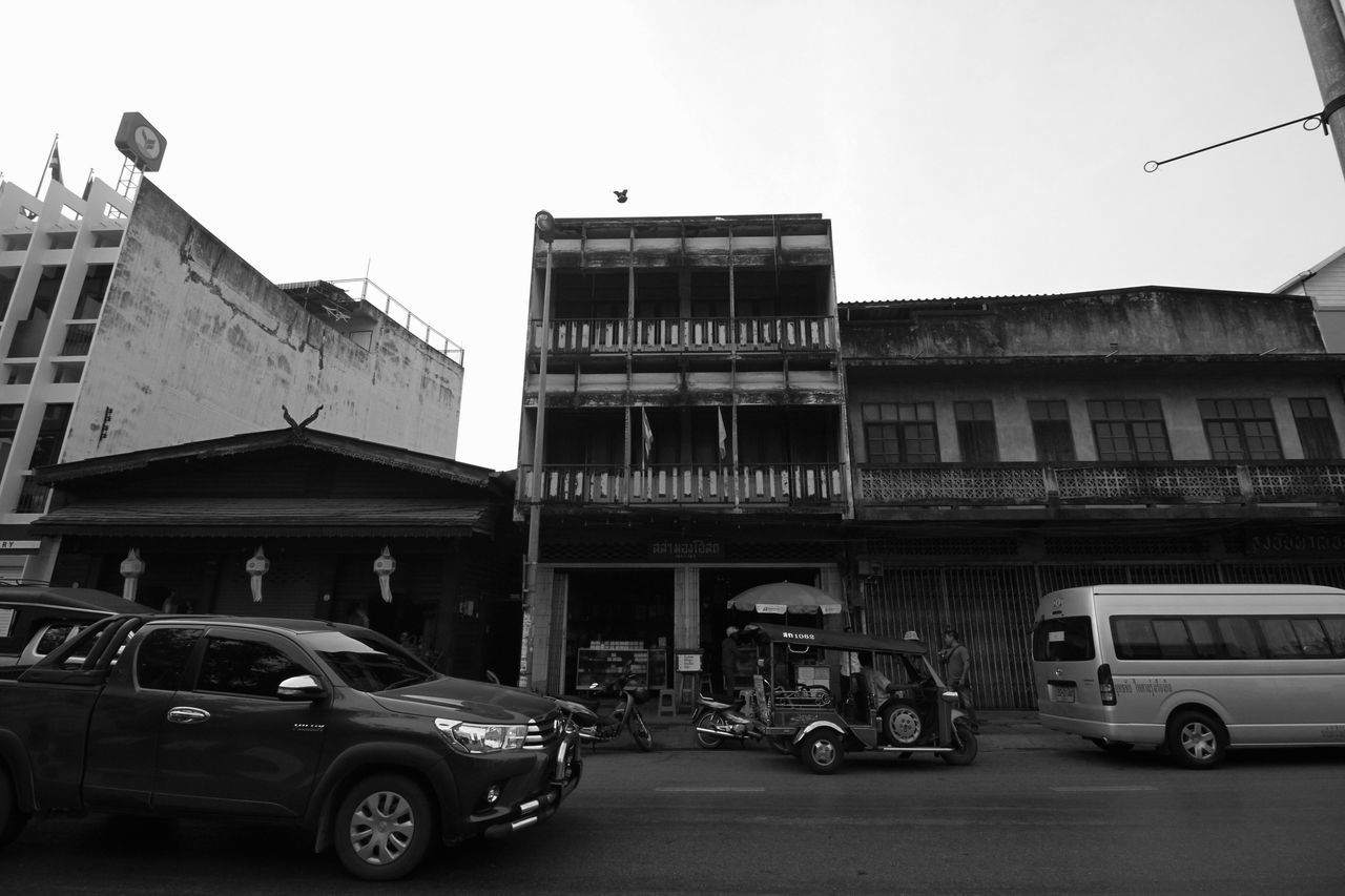 VEHICLES ON ROAD AGAINST BUILDINGS