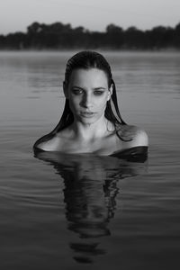 Portrait of young woman swimming in lake at dusk