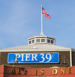 Low angle view of sign flag against blue sky