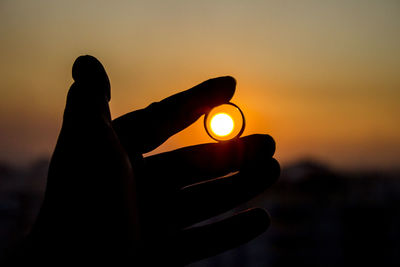 Close-up of silhouette hand against sky during sunset