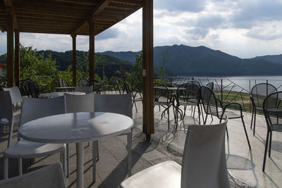 Empty chairs and tables at restaurant against sky