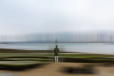 Rear view of man standing on water against sky