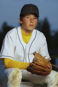 Portrait of a boy in white baseball uniform with his glove