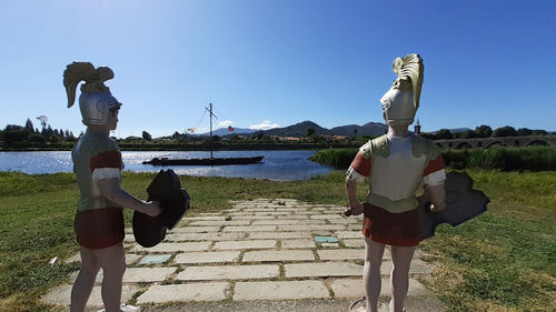 Rear view of woman walking on statue by water against sky