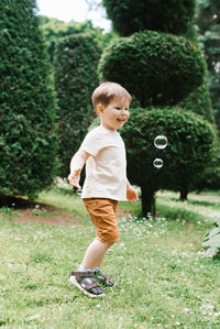 Emotional portrait of a happy and cheerful three-year-old little boy running after soap bubbles
