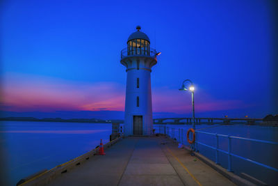 Lighthouse by sea against sky at sunset