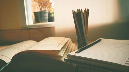 Close-up of open book and colored pencils on table at home