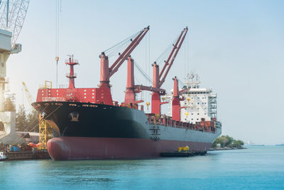 Cranes at commercial dock against sky