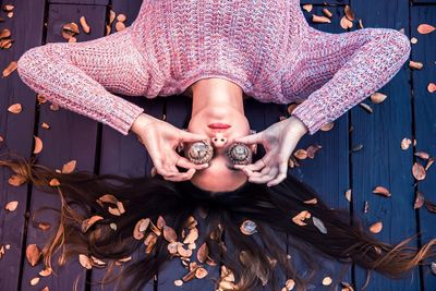 High angle view of woman with eyes covered by acorns on boardwalk