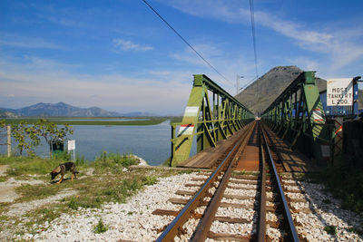 View of railroad tracks by water against sky
