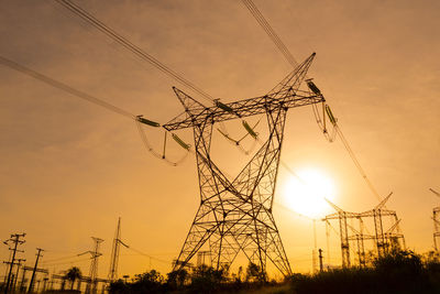Low angle view of silhouette electricity pylon against sky during sunset