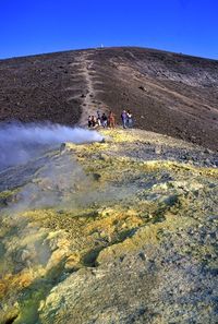 People on land against clear blue sky