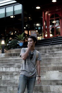 Young man looking away while standing on staircase