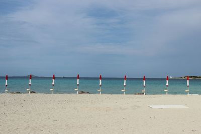 Closed parasols on shore at beach against sky