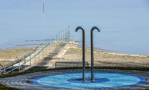 Swimming pool by sea against blue sky