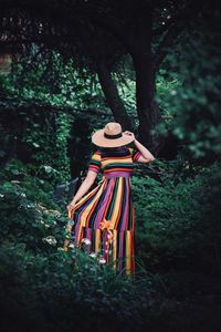 Rear view of woman standing by trees in forest