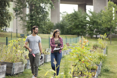 Mid adult couple examining plants at urban garden