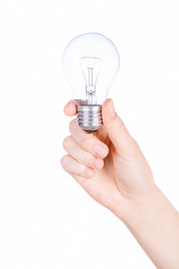 Close-up of hand holding light bulb against white background