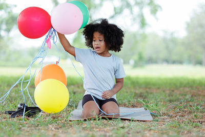 Girl holding balloons in field