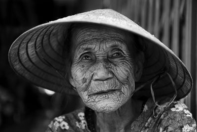 Close-up portrait of senior woman wearing asian style conical hat