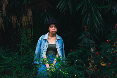 Portrait of young woman standing by plants