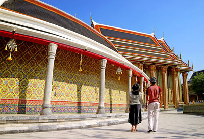 Couple walking along the circular gallery of wat ratchabophit buddhist temple, bangkok, thailand