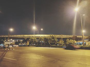 Illuminated street against sky at night