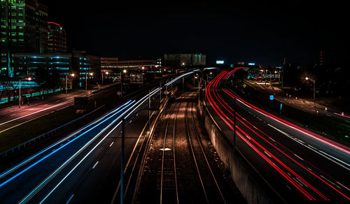 Light trails on city street against clear sky at night