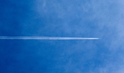 Low angle view of vapor trail against blue sky