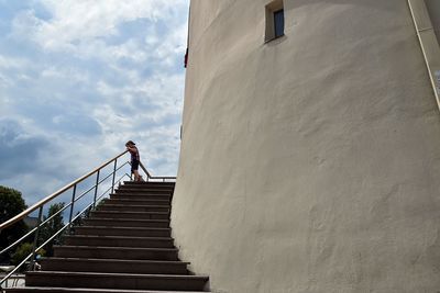 Low angle view of man standing on staircase against sky