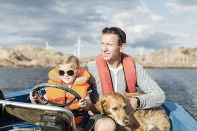 Girl driving motorboat with father and dog in baltic sea