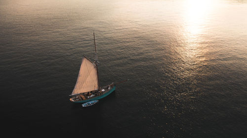 Aerial view above a luxury sailing yacht sailing towards the light in a concept of hope