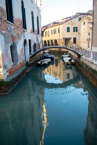 Arch bridge over canal amidst buildings in city