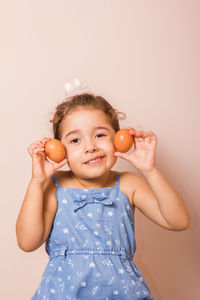 Portrait of smiling girl holding apple against white background