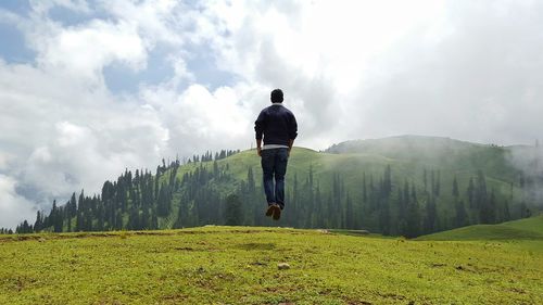 Man standing on field against cloudy sky