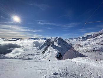 Scenic view of snow covered mountains against bright sun