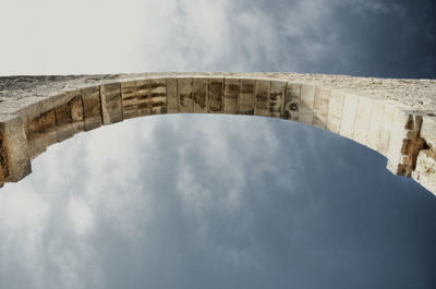 Low angle view of arch bridge against cloudy sky