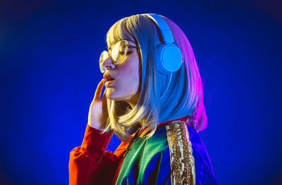 Young woman with headphones standing against black background