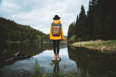 Rear view of man standing by lake