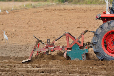 Red tractor plowing groove in field thailand.